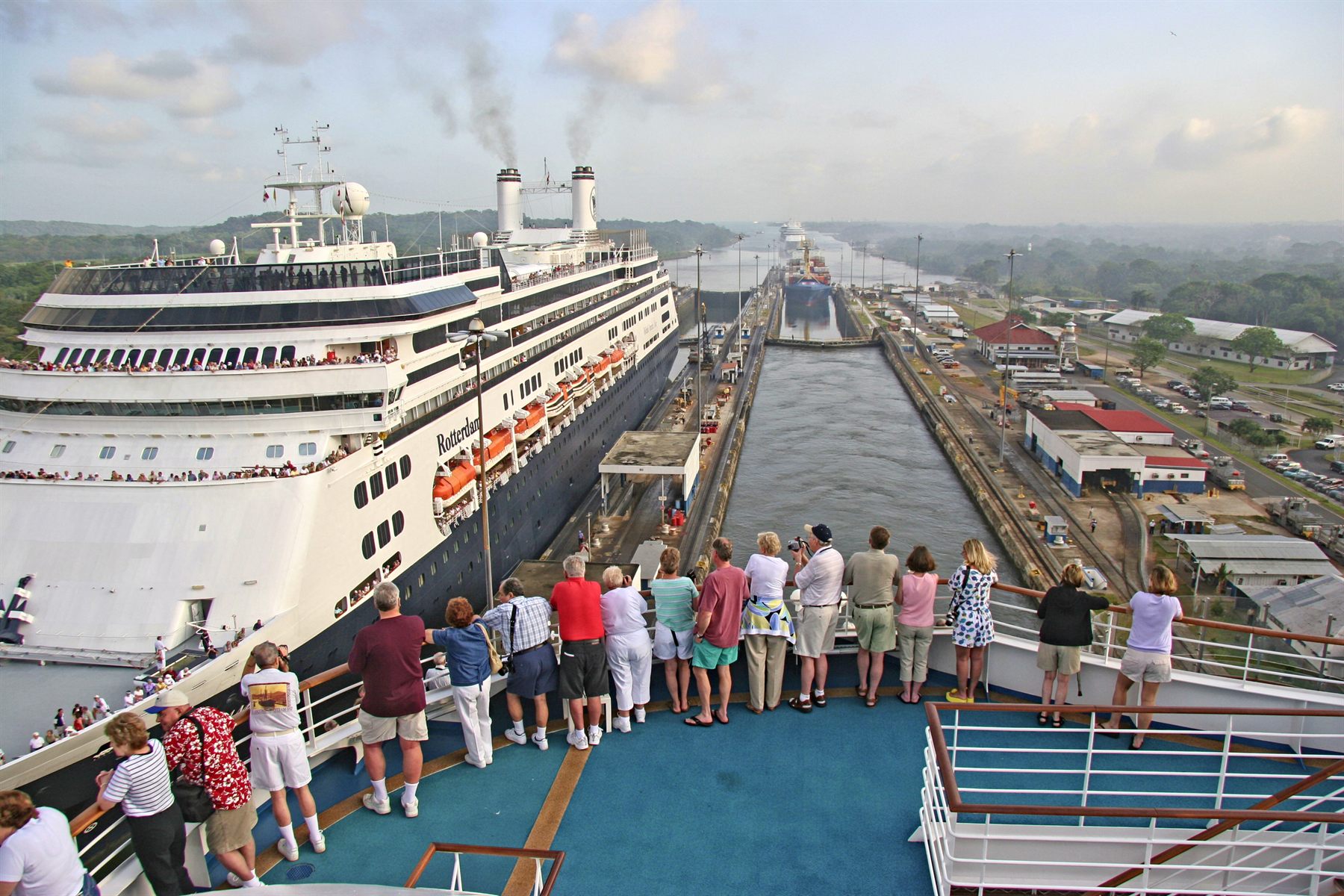 Passengers on a ship’s bow watching another cruise ship in the neighboring Panama Canal lock